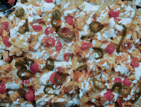 Buffalo Chicken Nachos fully dressed with jalapeno and tomatoes