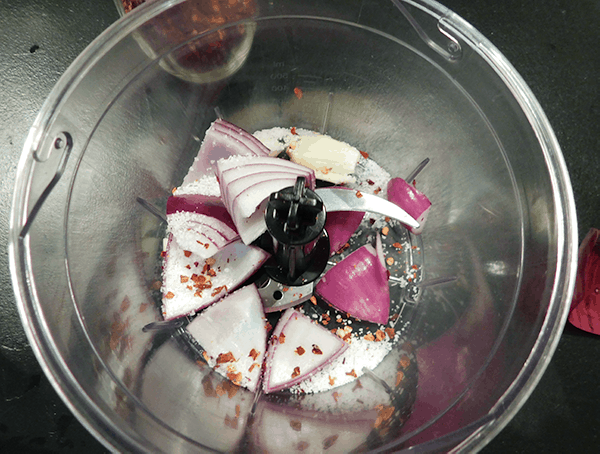 Red onion and garlic in food processor prepping Chimichurri Sauce