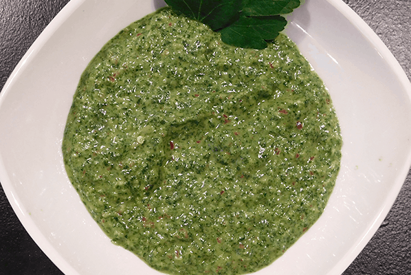 Green Chimichurri Sauce in a white bowl on a black background