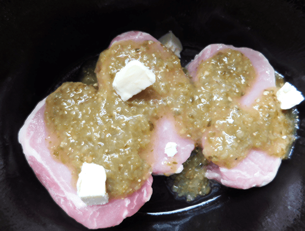 Pork chops in crock pot with green salsa and butter on top