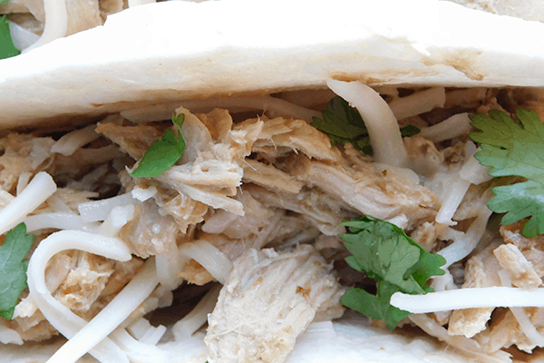 Close up of a pork salsa verde taco with cheese and cilantro