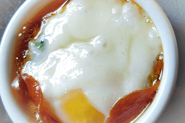 Closeup of baked egg in white ramekin