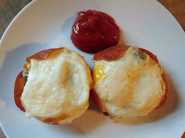 Two baked eggs on white plate with hot ketchup
