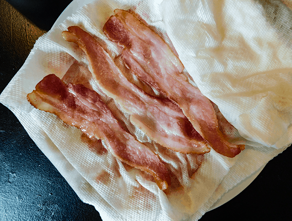 Partially cooked bacon on paper towels