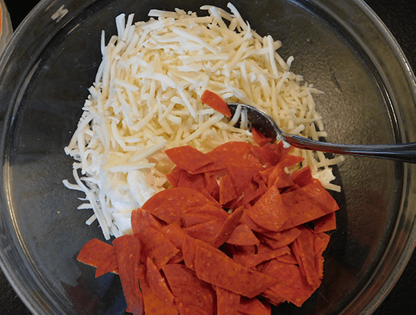 Cheeses and pepperoni in clear glass bowl