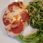Pepperoni Pizza Chicken on a white plate with zoodles and steamed broccoli