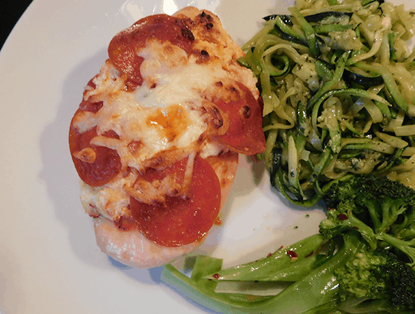 Pepperoni Pizza Chicken on a white plate with zoodles and steamed broccoli
