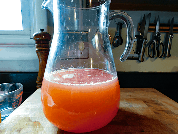 Mixed Strawberry Lemonade on Chopping block in clear pitcher