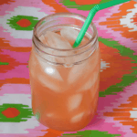 Strawberry Lemonade in small mason jar with a green bendy straw on a multicolored background