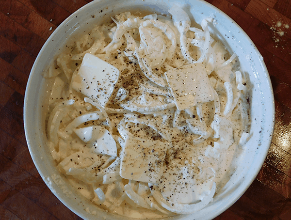 Scalloped Onions in a round white casserole dish ready for the oven