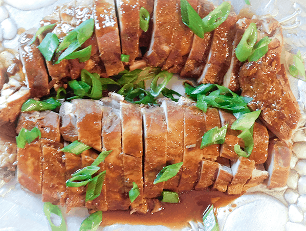Sliced Asian Pork Tenderloin with sauce on a silver platter