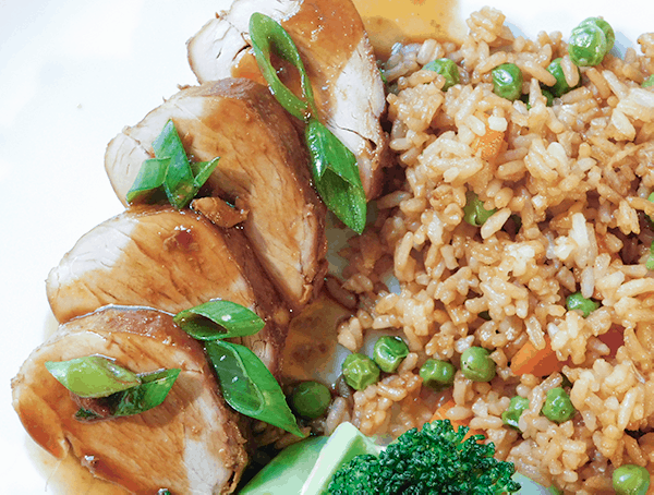 Asian Pork Tenderloin next to fried rice with sauce