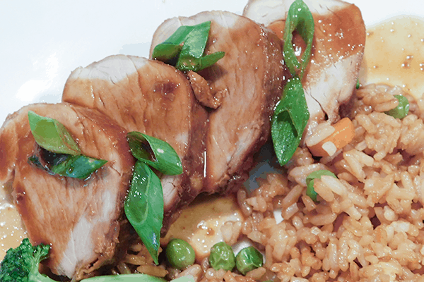 Pieces of Asian Pork Tenderloin on a plate with rice
