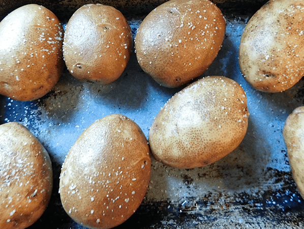 Whole salted potatoes on a sheet pan ready for the oven