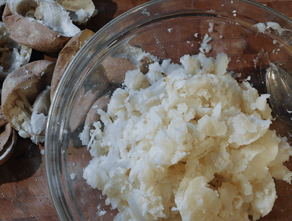 Baked potato innards are in clear glass bowl ready to be mashed