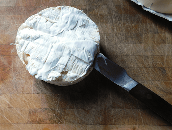 Brie being cut for Maple Walnut Baked Brie