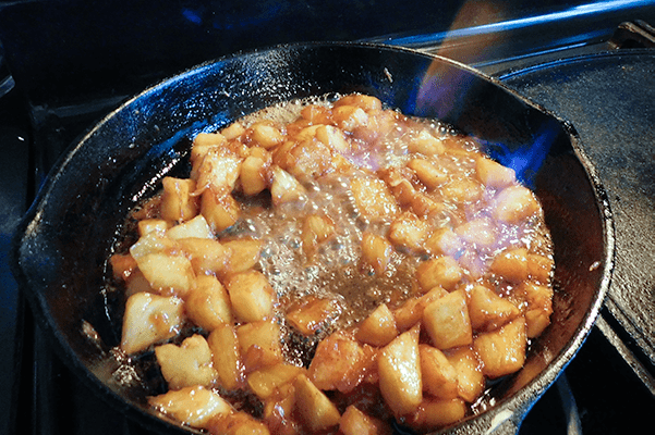 Pineapple Butter Rum Sundae topping flaming in a cast iron skillet