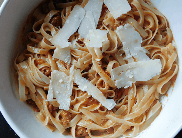 Sausage Ragu in a white bowl with shaved parmesan