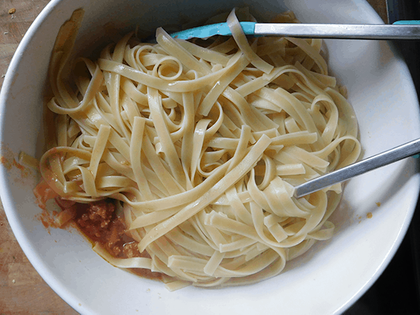 Noodles in white bowl on top of Sausage Ragu