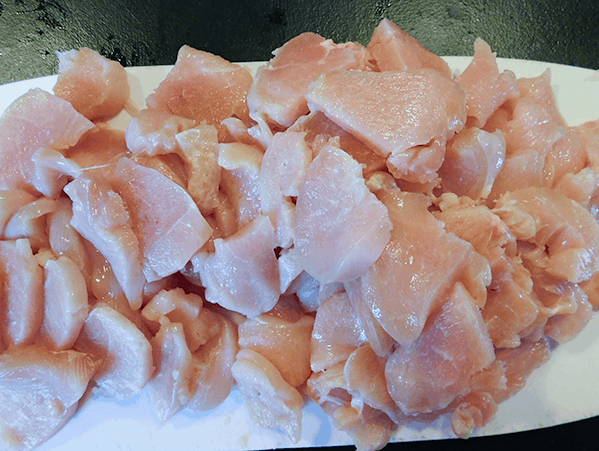 Sliced chicken on a white plastic chopping board