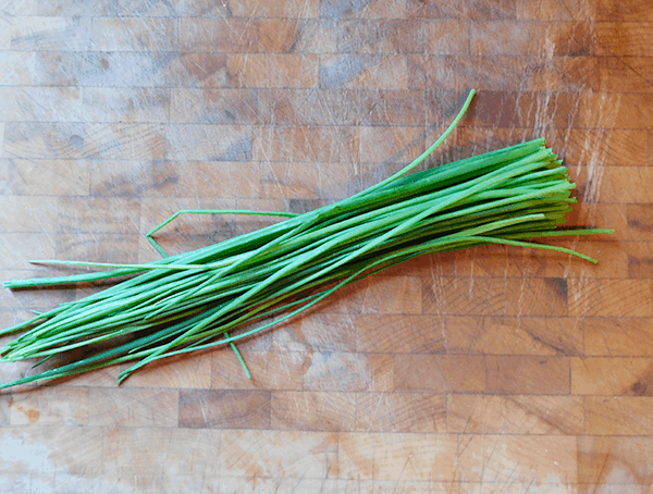 Bunch of chives on a chopping bloack ready for Chive Chicken