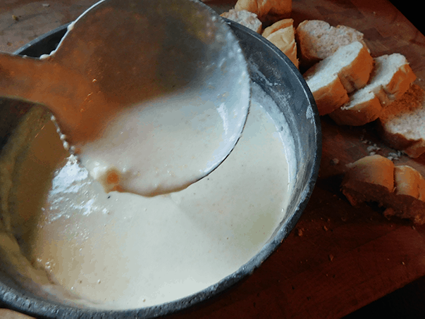 Garlic Alfredo Sauce in pan with ladle spooning it out