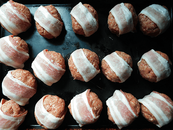 Meatballs with bacon on a baking sheet 