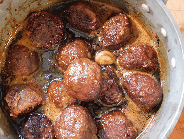 Cooked Mongolian Meatballs in a saucepan with sauce and garlic