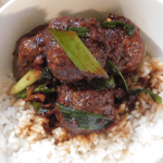 top view of Mongolian Meatballs in a white bowl on top of rice