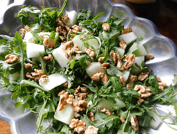 Arugula, melon and walnuts wait for ricotta cheese on a platter