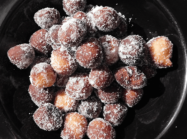 Donut Holes rolled in sugar in a black bowl