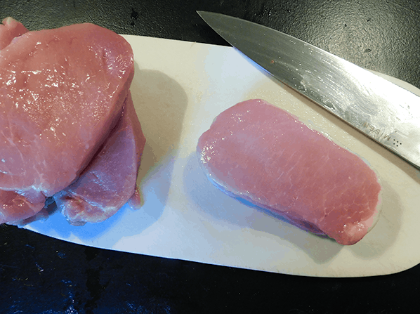 Boneless pork chops on a white cutting board