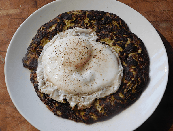 Zucchini Pancake on a white plate topped with a fried egg
