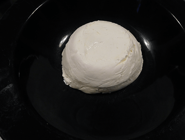 Cream cheese molded into a circle in a serving bowl. 