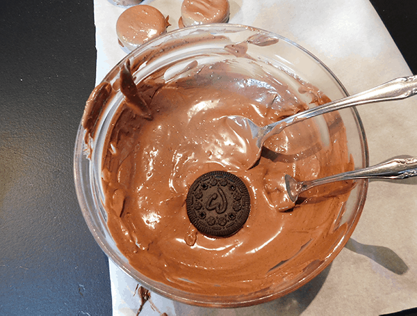 Dipping chocolate sandwich cookies in chocolate