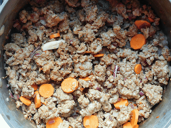 Sausage with garlic, onion and carrots in a soup pot