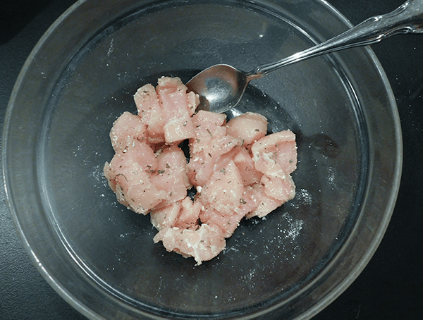 Chicken in a glass bowl sprinkled with ranch dressing mix