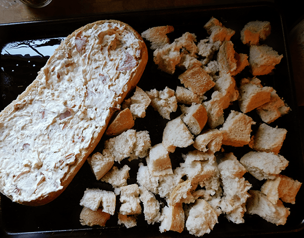 Uncooked pizza dip in an Italian bread loaf on a baking sheet