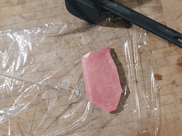 Pork chop cut in half ready to pound